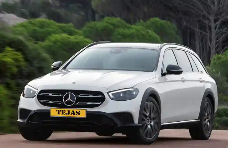 A white Mercedes-Benz car with a sleek design parked on a road surrounded by greenery.