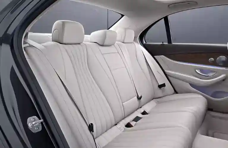 Luxury car interior featuring a spacious back seat with light-colored leather upholstery and modern design elements.