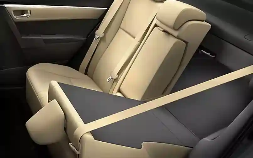 Beige leather backseat of a car with a folded-down center armrest and seatbelt visible.
