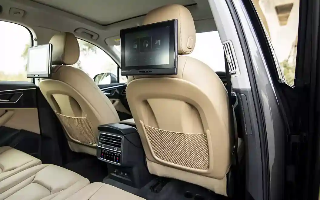 Elegant car interior featuring beige leather seats, backseat entertainment screens, and modern climate controls.