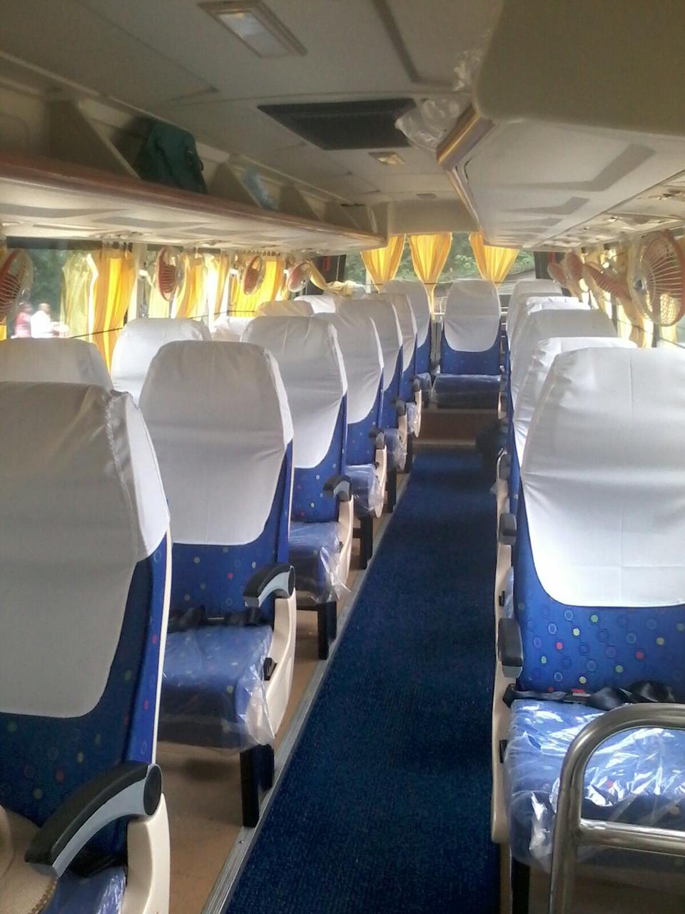 Clean, empty bus interior with blue seats covered in white protective covers and yellow curtains at the windows.