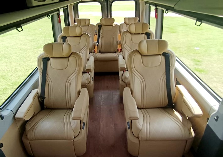 Interior of a shuttle bus featuring plush tan seats arranged in rows, with a modern, clean design and natural light.