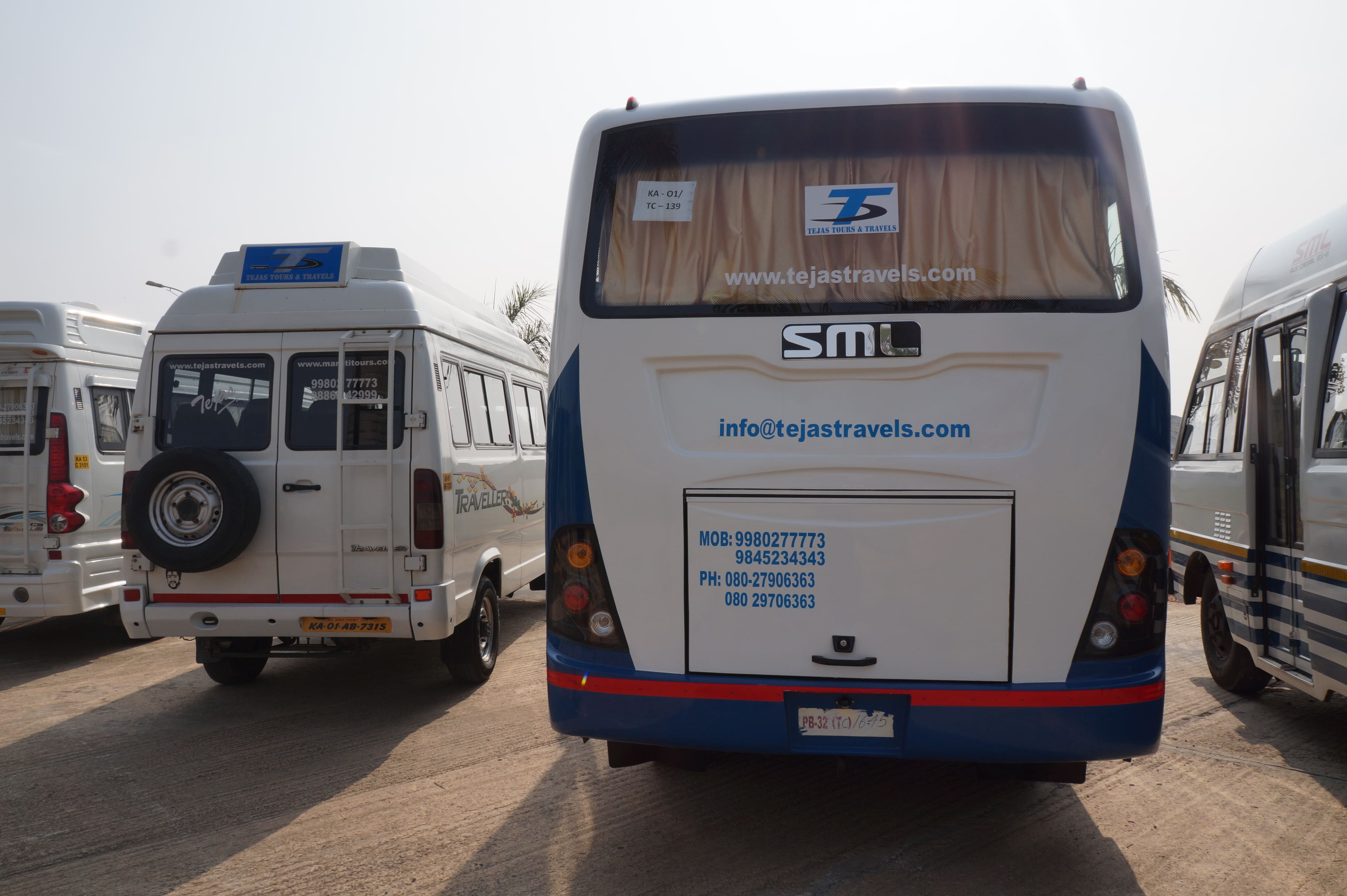 Two large travel vehicles parked side by side, featuring signage for Tejas Travels, with clear skies in the background.