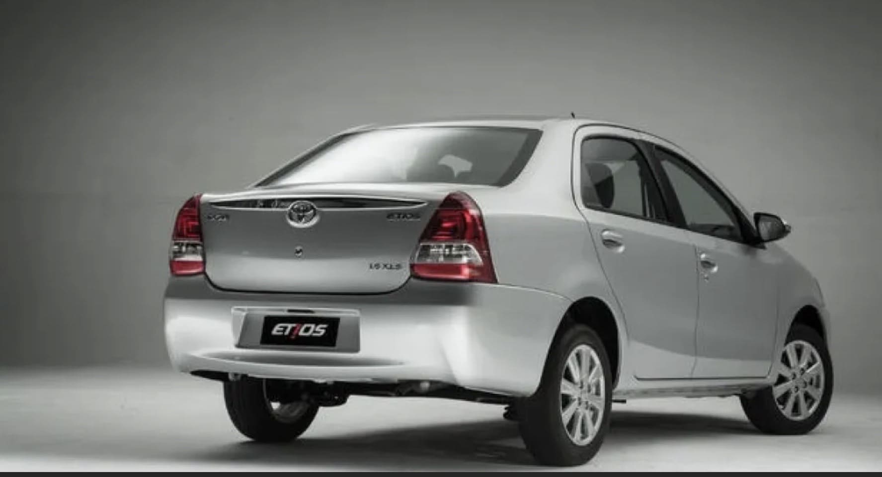Silver Toyota Etios sedan shown from the rear, featuring a sleek design against a neutral gray background.